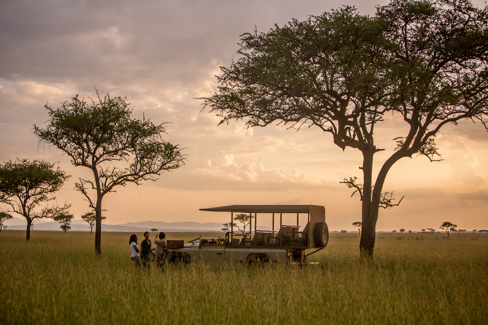 game drive vehicle at sunset in Serengeti with sundowners at Singita Faru Faru lodge Serengeti