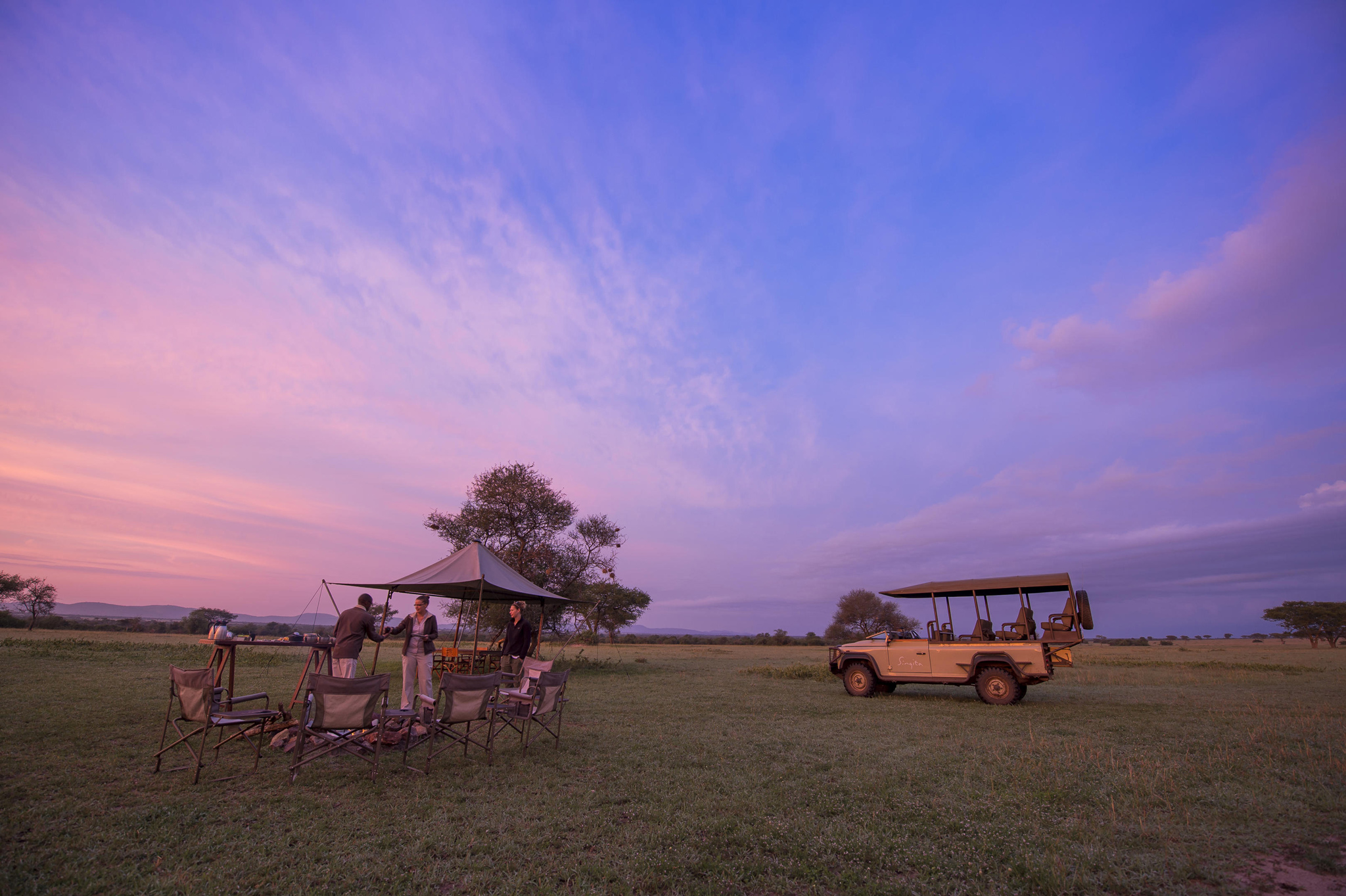 sundowners on the plain at colourful sunset by Singita Faru Faru lodge Serengeti