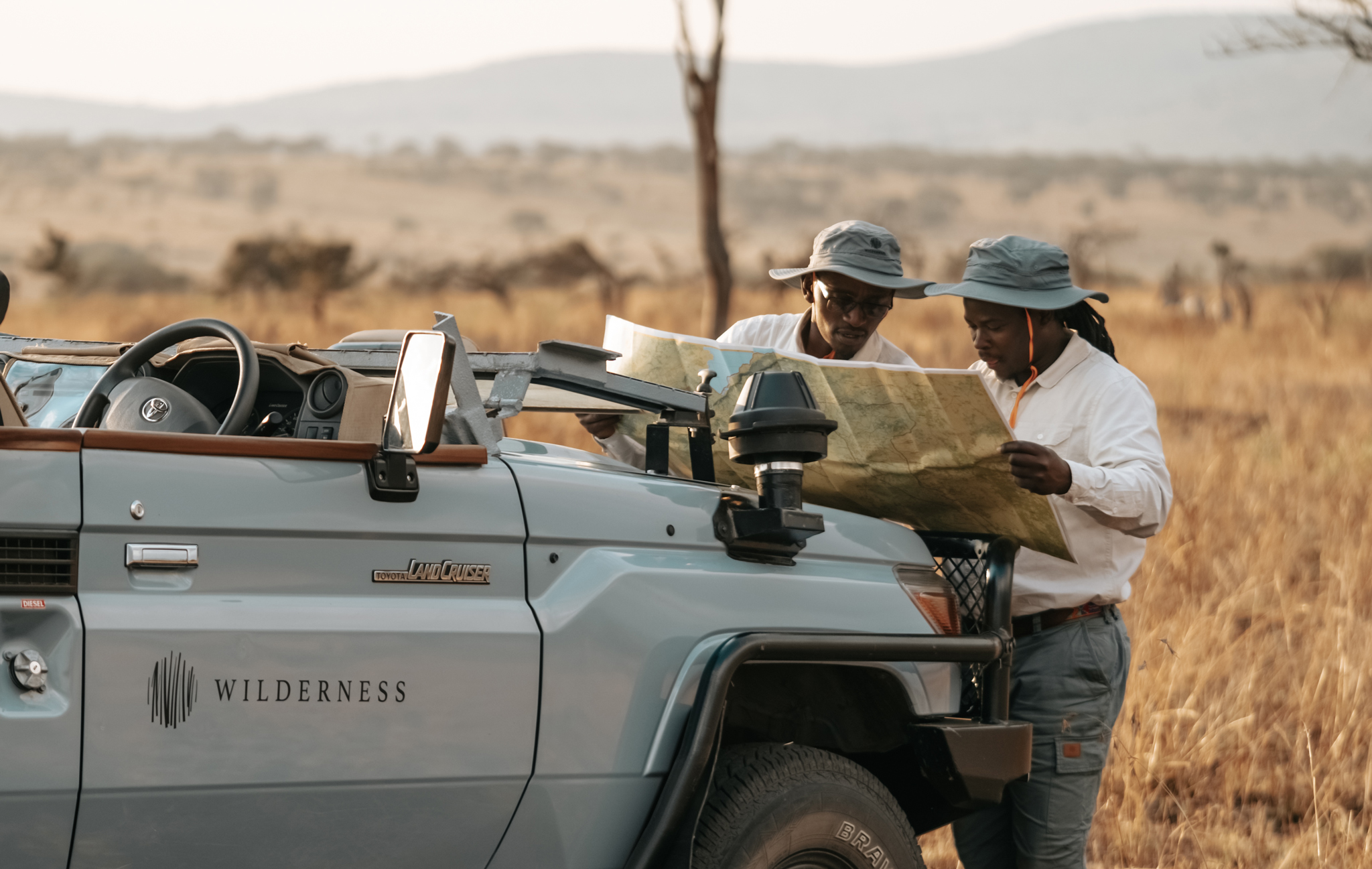 trackers reading a map by the safari vehicle of Wilderness Usawa tented camp Serengeti